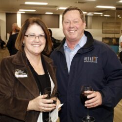 Image of man and woman holding wine glasses and smiling at the camera